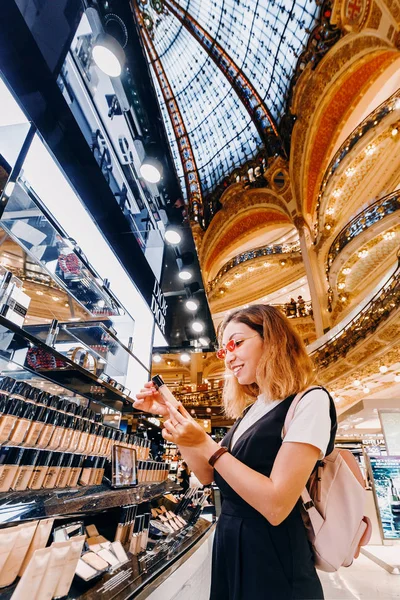 27 juli 2019, Parijs, Frankrijk: Aziatisch meisje kiest cosmetica in het winkelcentrum Galerie Lafayette in Parijs — Stockfoto