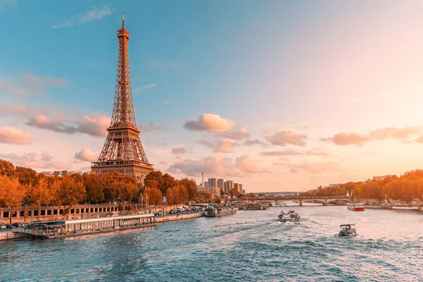 The main attraction of Paris and all of Europe is the Eiffel tower in the rays of the setting sun on the bank of Seine river with cruise tourist ships