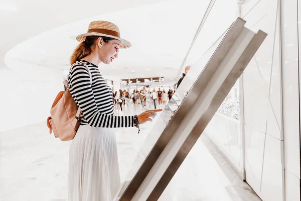 Азиатская девушка использует сенсорный экран терминала, чтобы найти правильный бутик в большом торговом центре — стоковое фото