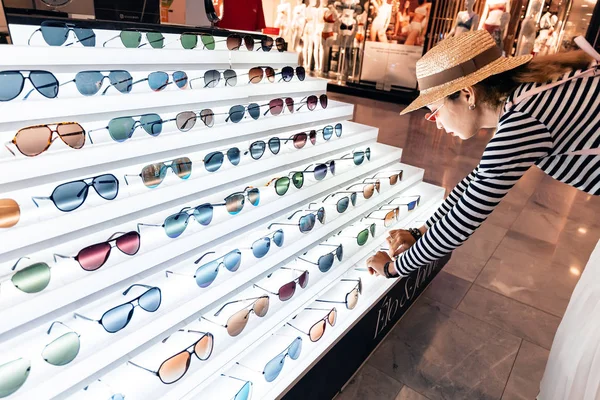 28 июля 2019 года, Париж, Франция: счастливая молодая женщина выбирает солнцезащитные очки в магазине — стоковое фото