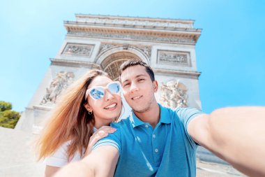 Mutlu bir adam ve bir kız sarılmak ve Paris'te Arc de Triomphe karşı selfie fotoğraf çekmek. Balayı ve Fransa'da birlikte bir gezi
