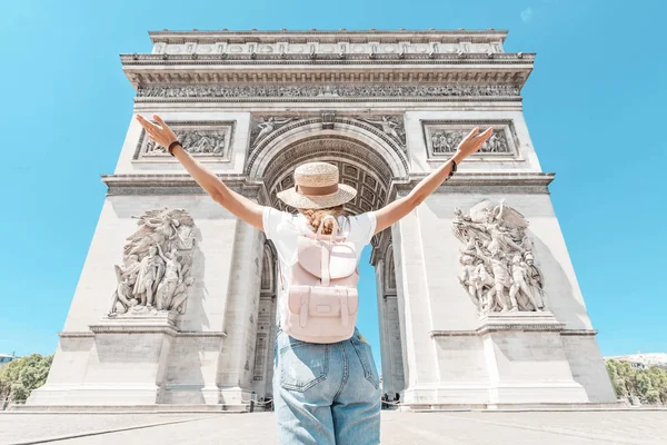 Happy Asian tourist girl enjoys the view of the majestic and famous Arc de Triomphe or Triumphal arch. Solo Travel and voyage to Paris and France