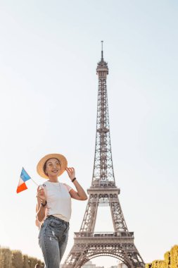 Happy asian woman traveler posing at Mars Field at the background of majestic Eiffel tower. Tourism and lifestyle in France and Paris. Vacation in Europe.