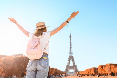Happy asian woman traveler posing at Mars Field at the background of majestic Eiffel tower. Tourism and lifestyle in France and Paris. Vacation in Europe.