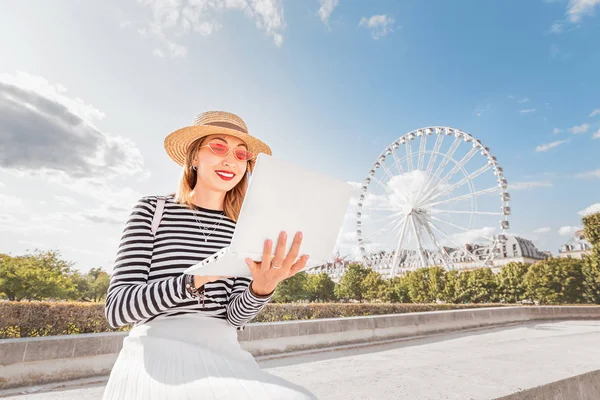 Feliz asiática autónoma chica o estudiante de aprendizaje de un idioma a través de Internet sentado con un ordenador portátil en el parque de atracciones con noria rueda en el fondo —  Fotos de Stock