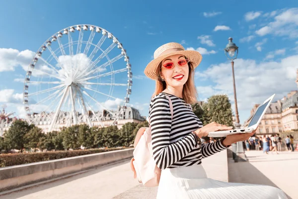 Glücklich asiatisches selbstständiges Mädchen oder Student, das eine Sprache über das Internet lernt, sitzt mit einem Laptop im Vergnügungspark mit Riesenrad im Hintergrund — Stockfoto