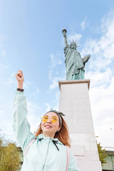 Menina asiática feliz viajante engraçado posando no fundo da famosa Estátua da Liberdade. O conceito de turismo e imigração — Fotografia de Stock