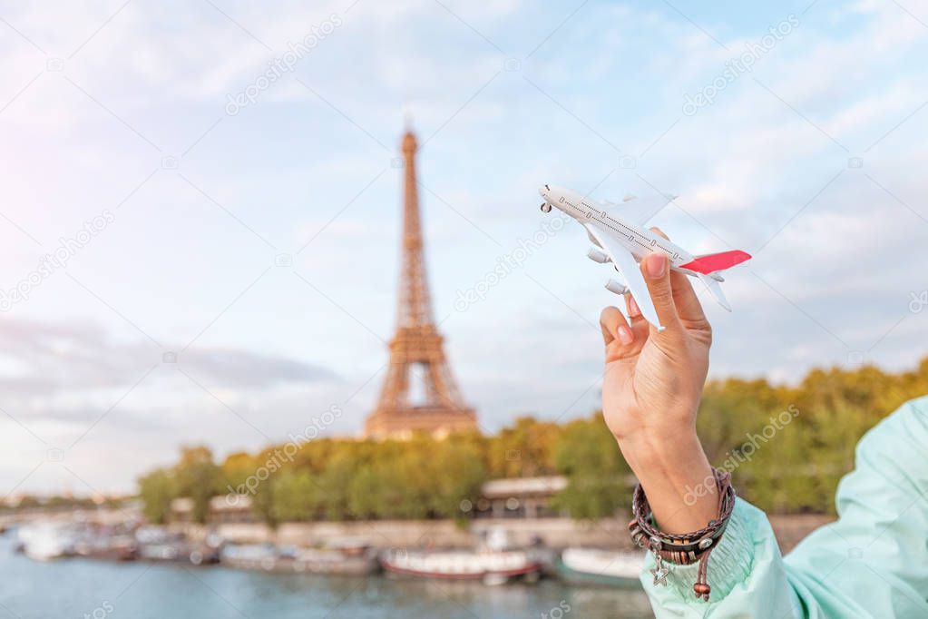 Girl playing with a toy plane on the background of the Eiffel tower. Concept of air travel and tourism