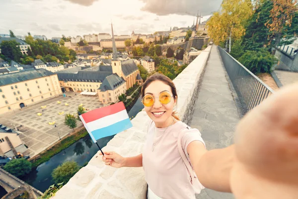 Азійська туристична дівчина проводить селфі з прапором Люксембургу на тлі старої чверті міста Грюнд і церкви.. — стокове фото
