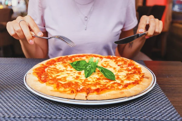 Mladá dívka jíst lahodnou pizzu se sýrem a zeleninou v pizzerii — Stock fotografie