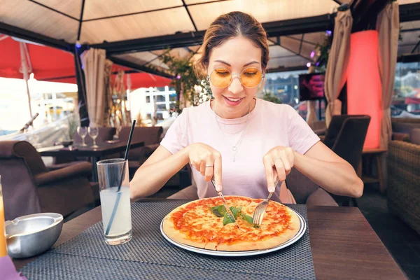 Young girl eating delicious pizza with cheese and greens in pizzeria — Stock Photo, Image