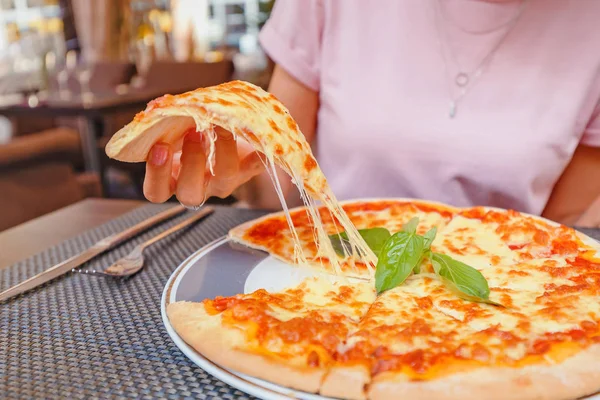 Mladá dívka jíst lahodnou pizzu se sýrem a zeleninou v pizzerii — Stock fotografie