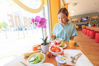 04 Ağustos 2019, Saarbrucken, Almanya: Asyalı Kadın otel restoranında kahvaltı yapıyor