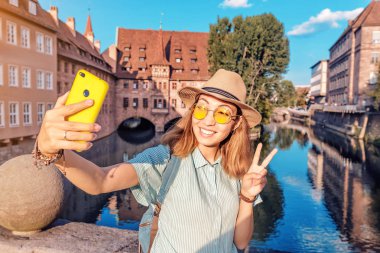 Mutlu Asyalı kadın akıllı telefonuyla Nuremberg 'deki Peignitz nehrinin fotoğrafını çekiyor.