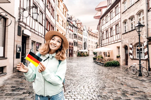 Junge asiatische Touristin mit Deutschland-Fahne in der Nähe der berühmten Fachwerkstraße in der Nürnberger Altstadt unterwegs — Stockfoto