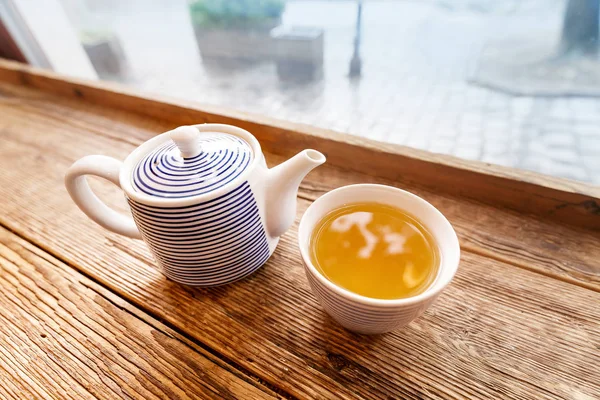 Чайник и чашка чая на столе у окна — стоковое фото