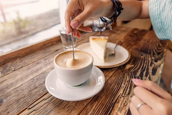 Чашка капучино с пеной в форме сердца и кусочек чизкейка на старинном деревянном фоне в кафе — стоковое фото