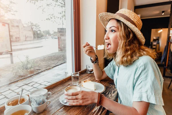Красивая молодая женщина ест торт и пьет кофе в ретро кафе — стоковое фото