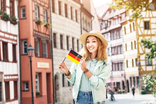 Ung asiatisk kvinna turist reser med tysk flagga nära den berömda korsvirkesgatan i Nürnberg gamla stan — Stockfoto