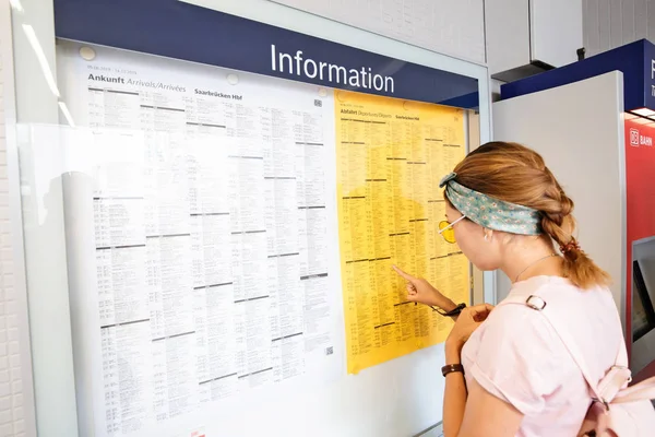 02 августа 2019, Мюнхен, Германия: пассажирка смотрит на распечатанное расписание поездов — стоковое фото