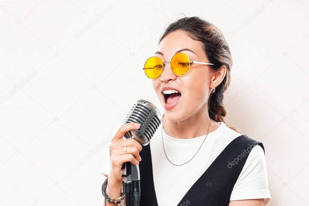 Asian girl sings into the microphone. The concept of vocal school and karaoke entertainment