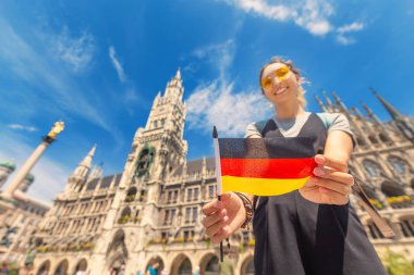 Alman bayrağı taşıyan mutlu bir kız Münih 'teki belediye binasının arka planında poz veriyor. Almanya 'ya seyahat ve göç