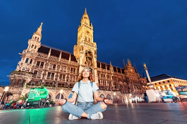 Девушка-туристка наслаждается ночным видом на освещенное готическое здание старой ратуши в Мюнхене. Осмотр достопримечательностей Германии и Баварии — стоковое фото