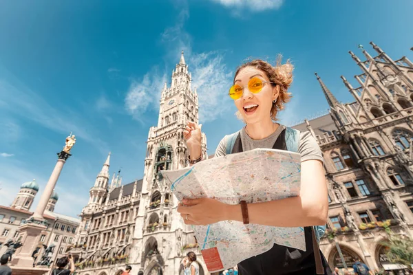 Щаслива жінка з картою, яка шукає краєвиди та цікаві місця в мюнхенському місті з ратушею на задньому плані. — стокове фото