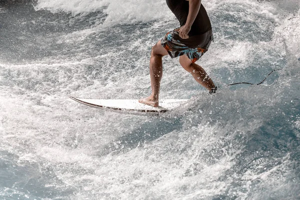 Fechar as pernas de um atleta surfando nas ondas do mar — Fotografia de Stock