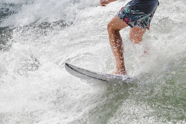 Fechar as pernas de um atleta surfando nas ondas do mar — Fotografia de Stock