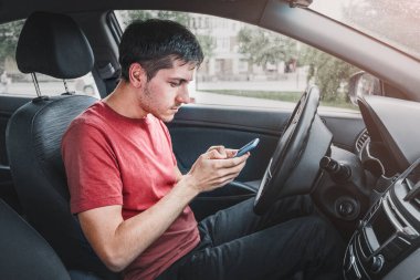 Direksiyondaki adam yol durumundaki konsantrasyonunu kaybediyor ve bir sohbette akıllı bir telefonda SMS yazarken takılıp kalıyor. Tehlikeli bir trafik kazası riski var.