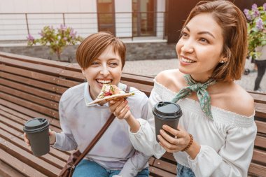 Kız arkadaşlar paket pizzayı paylaşır. Lezzetli fast food yerler, kahve içerler ve şehir meydanında sosyalleşirler.