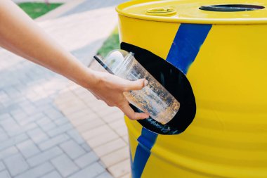 Kadın kullanılmış plastik bardağı çöpe atıyor. Atık geri dönüşümü ve çevre kirliliği kavramı