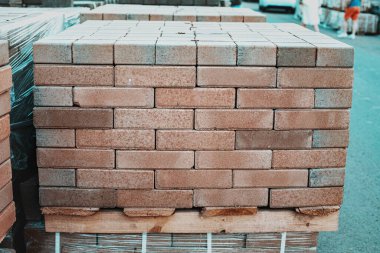 Sokaktaki bir inşaat deposunda yeni üretilen kırmızı tuğla paketleri. Onarım ve inşaat malzemeleri kavramı
