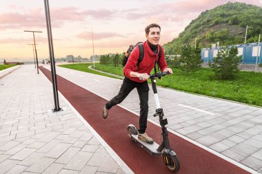 Genç bir adam hızlı ve güvenli bir şekilde işe gitmek için toplu taşımayı değil, kişisel ya da kiralık bir elektrikli scooter 'ı seçer.