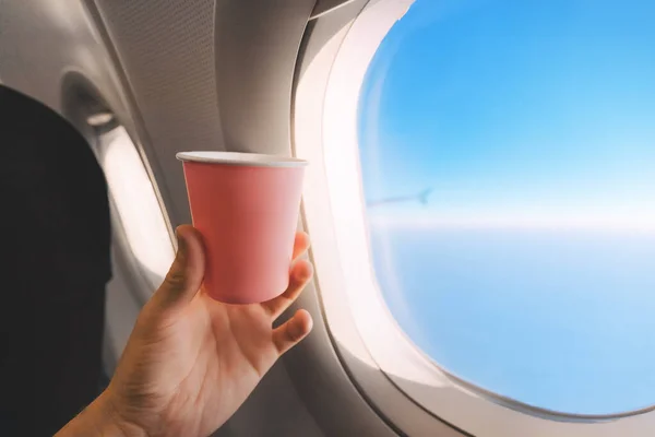 Bir Uçak Yolcusunun Eli Penceredeki Mavi Gökyüzüne Karşı Bir Fincan — Stok fotoğraf