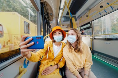 02 Eylül 2020, Moskova, Rusya: Moskova otobüsünde tıbbi maskelerle fotoğraf çeken iki arkadaş. Coronavirus kısıtlamaları ve toplu taşımacılıkta karantina