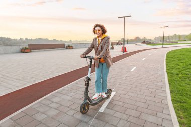 Modern elektrikli scooter 'ı olan bir kadın. Şehir Yaşam Tarzı ve Ulaşım Konsepti