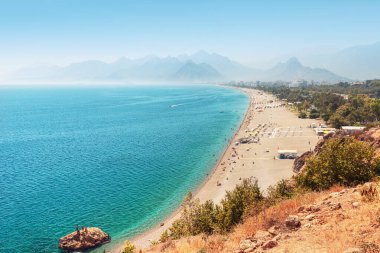 Antalya 'daki ünlü uzun Konyaalti plajı. Arkasında Taurus dağları olan Türk tatil beldesi ve Riviera.