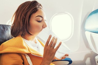Asyalı bir kadın yolcu uçakta türbülans sırasında şiddetli bir mide bulantısı krizinden muzdarip. Kadın uçuş sırasında deniz tutması ve hava yastığıydı.
