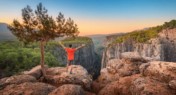 A free man with open arms stands on top of a cliff above the gorge of Tazi canyon in Turkey. Solitude in nature and active solo travel and recreation