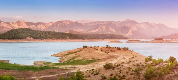 Panoramic inspirational and tranquil landscape in the rays of the sun in the morning. Idyllic nature with silhouettes of the Taurus mountains. Karacaoren lake in the Isparta region of Turkey.