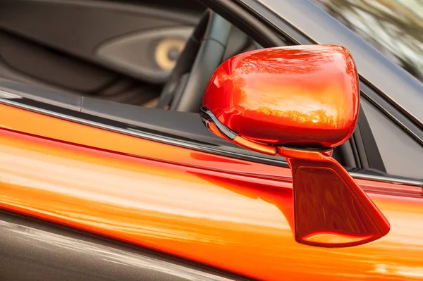 close-up of a driving mirror on a bright orange luxury sports car