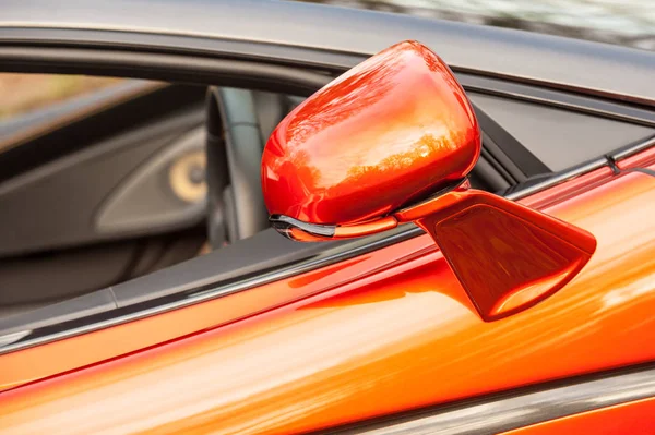 close-up of a driving mirror on a bright orange luxury sports car