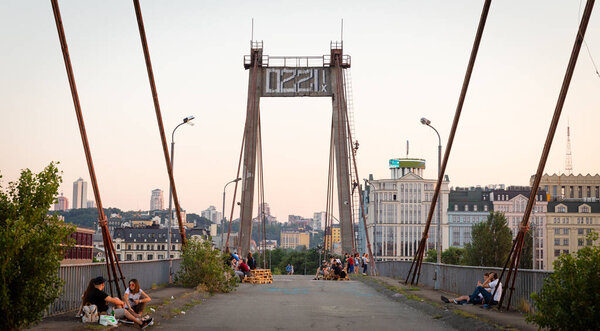 KIEV, UKRAINE - May 30, 2018:  People on cable-stayed Rybalsky bridge in the evening during sunset. Industrial district of Kiev, Ukraine