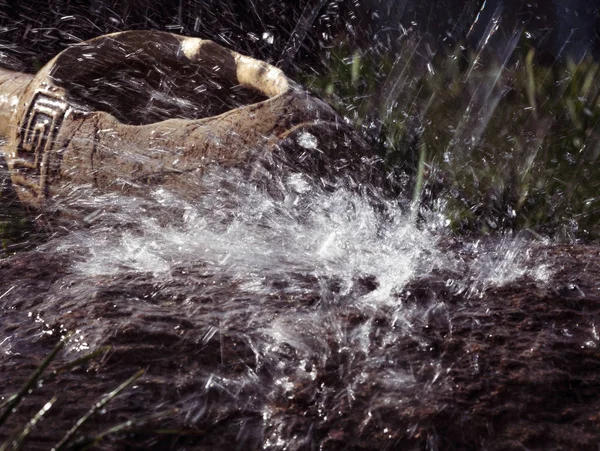 Wet stone and decorative antique urn in the rain. Rain water drop falling to the stone. Water is flowing and splashing around them.