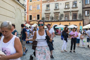 Lublin, Polonya - 27 Temmuz 2018: Kalabalık turist ve tatilciler Lublin eski şehir sokaklarında. Sopa ile genç kadın ve smartphone. Lublin Polonya'dokuzuncu büyük şehridir