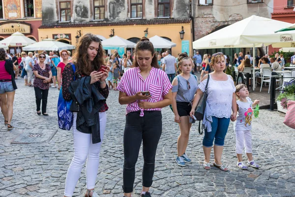 Lublin, Polonya - 27 Temmuz 2018: Kalabalık turist ve tatilciler Lublin eski şehir sokaklarında. İki genç kız akıllı. Lublin Polonya'dokuzuncu büyük şehridir