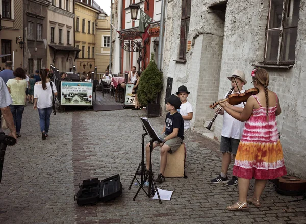 Lublin, Polonya - 27 Temmuz 2018: Kalabalık turist ve tatilciler Lublin eski şehir sokaklarında. Çocuk sokak müzisyenleri. Lublin Polonya'dokuzuncu büyük şehridir