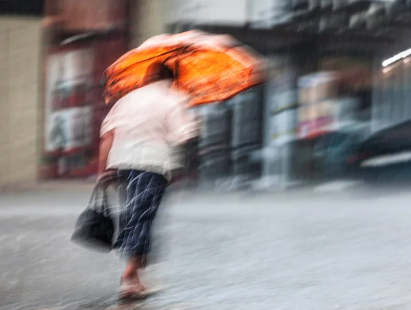 Kasıtlı Hareket Yağmurlu Günde Sokakta Yürürken Turuncu Şemsiye Ile Yalnız — Stok fotoğraf